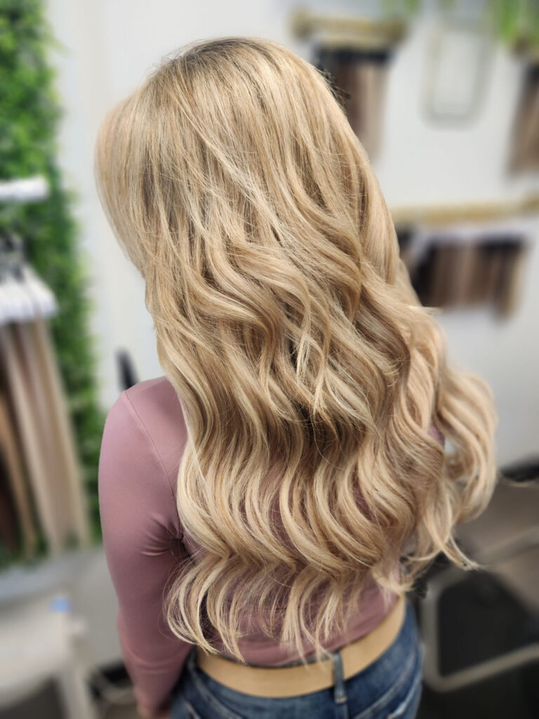Back view of long, golden-blonde wavy hair with extensions